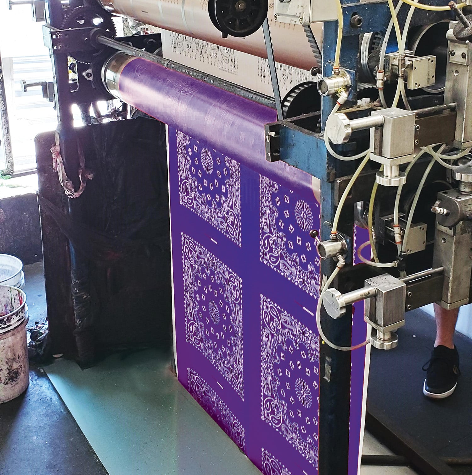 duplex 2 rgb - Purple Paisley A printing press machine feeding a roll of purple fabric with a white bandana pattern.