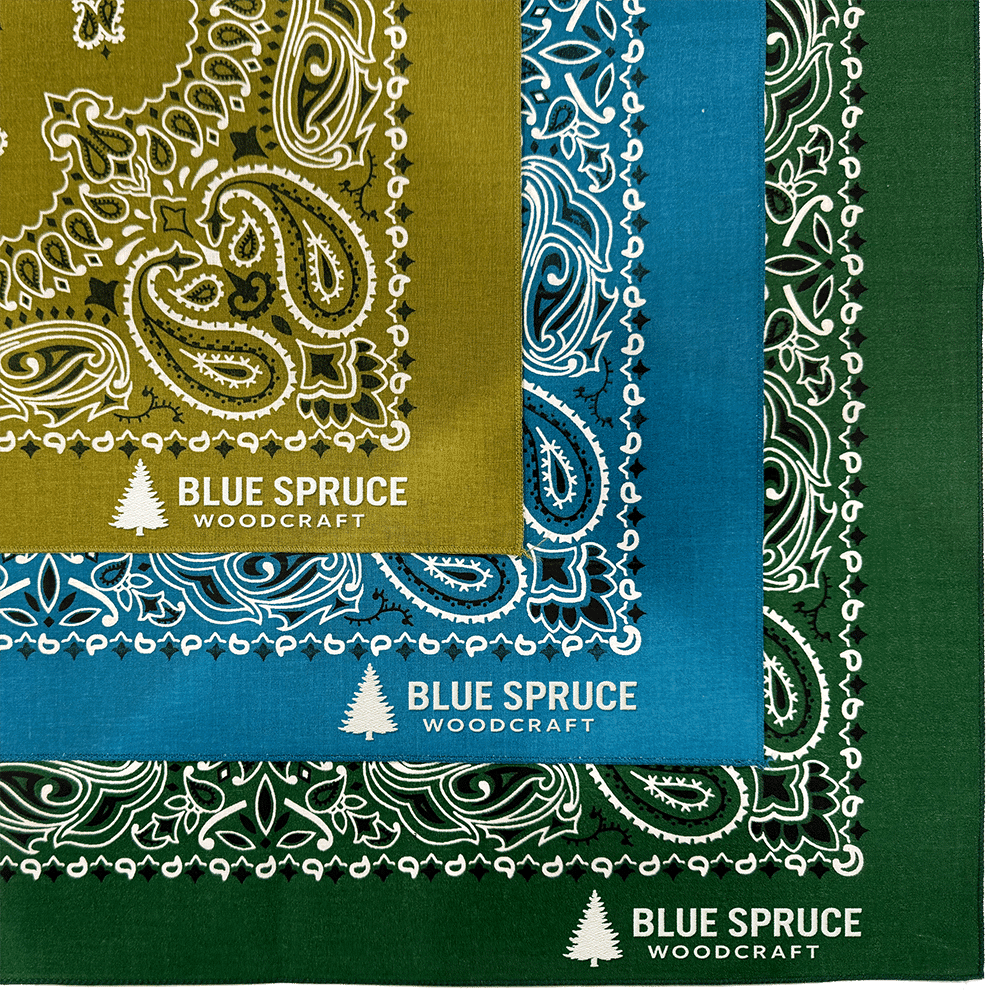 paisley-bandannas-with-embroidered-edge-logo2-2 Three bandanas in olive green, blue, and dark green, each with a white paisley pattern and the Blue Spruce Woodcraft logo.